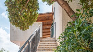 A staircase with patterned tiles leading to a wooden door. - Casa Bouganvillea con Terrazza by Wonderful Italy (Isola delle Femmine)