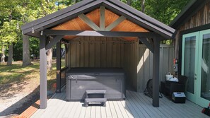 A hot tub under a wooden pergola on a wooden deck.