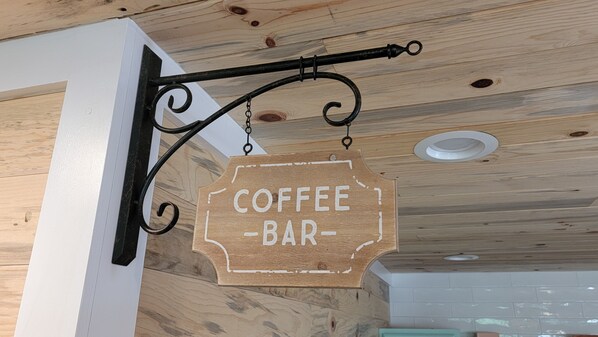 A wooden sign with the words "COFFEE BAR" hanging from a black metal fixture.