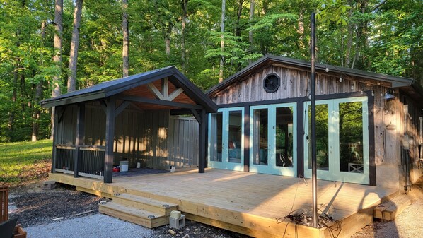A cabin with a wooden deck, large windows, and a porch.
