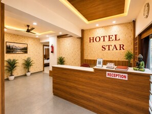 A hotel reception desk with a 'Hotel Star' sign, a reception area, a ceiling fan, and a framed picture on the wall.