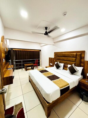 A modern hotel room with a large bed, wooden headboard, and a desk with a chair.