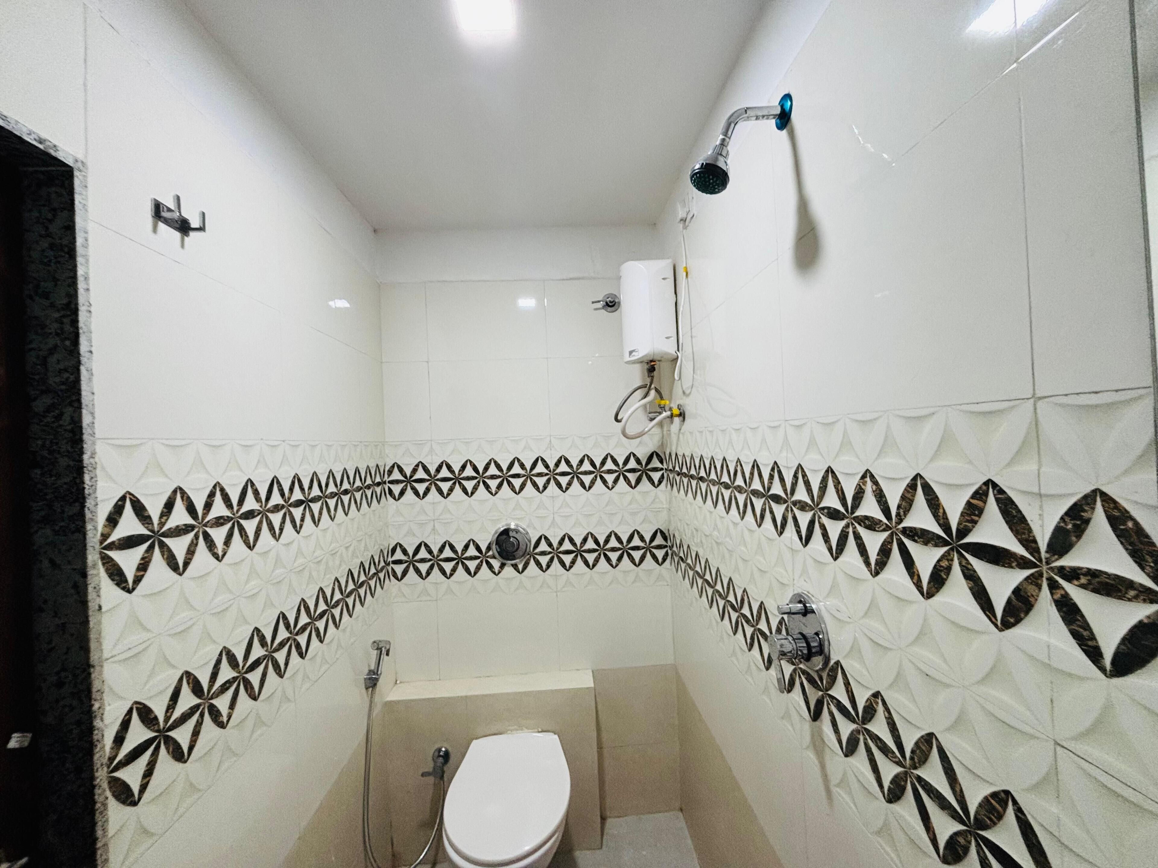 Un baño pequeño con inodoro blanco, ducha y baldosas decorativas blanco y negro.