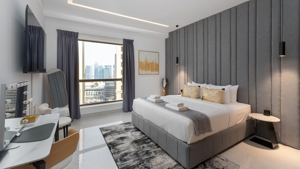 Une chambre moderne avec un grand lit, un bureau avec un ordinateur et une vue sur la ville.