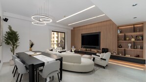 Un salon moderne comprenant un coin repas, un grand téléviseur à écran plat et un mur décoratif en bois.