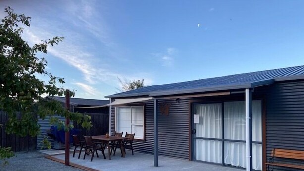 A modern single-story house with a covered patio, a dining table, and chairs. - Omarama Crib – Spotless Scenic Base for Families (Omarama)