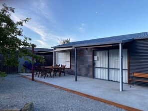 A modern single-story house with a covered patio, a dining table, and chairs. - Omarama Crib – Spotless Scenic Base for Families (Omarama)