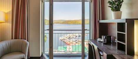 Una habitación con vista a un puerto deportivo, una silla, un escritorio con una planta y una lámpara.