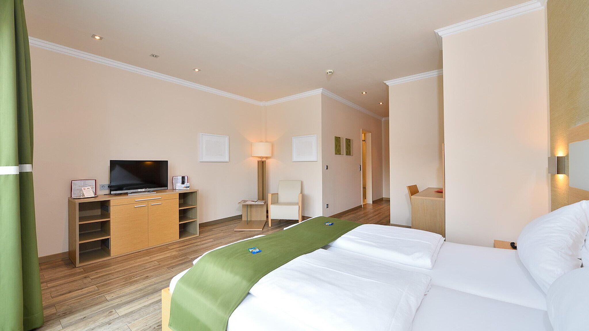 Een hotelkamer met een bed, een televisie, een bureau en een stoel.