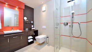A modern bathroom with a glass-enclosed shower, a vanity with a mirror, and a toilet. - Double room Seeblick with balcony (Heimbach)