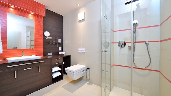 Une salle de bain moderne avec une douche à parois de verre, un meuble-lavabo avec un miroir et des toilettes.