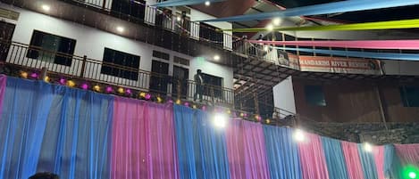Un escenario con cortinas coloridas y un cartel para el New Mandakini River Resort.