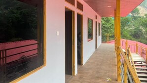 A corridor with large windows, wooden flooring, and a red ceiling. - New Mandakini River Resort (Ukhimath)