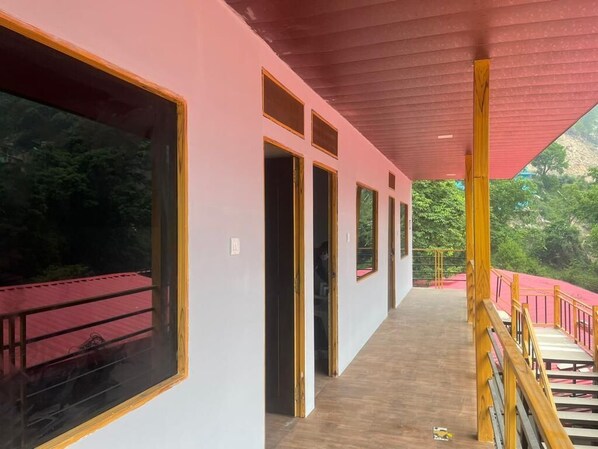 Un pasillo con ventanas amplias, suelo de madera y techo rojo.