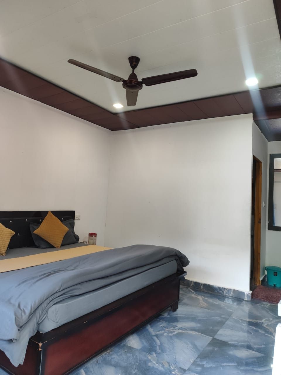 Une chambre à coucher avec un lit, un ventilateur de plafond et un sol carrelé.