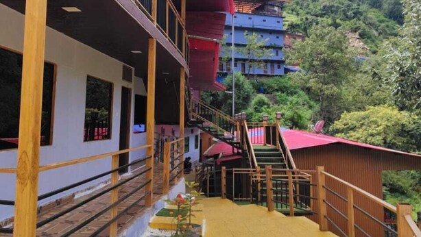 A multi-story building with a balcony, wooden railings, and a red roof. - New Mandakini River Resort (Ukhimath)