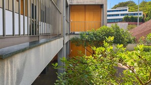 A modern building with a concrete facade, a wooden door, and a metal railing. - Titou Apartment Sea View (Machico)