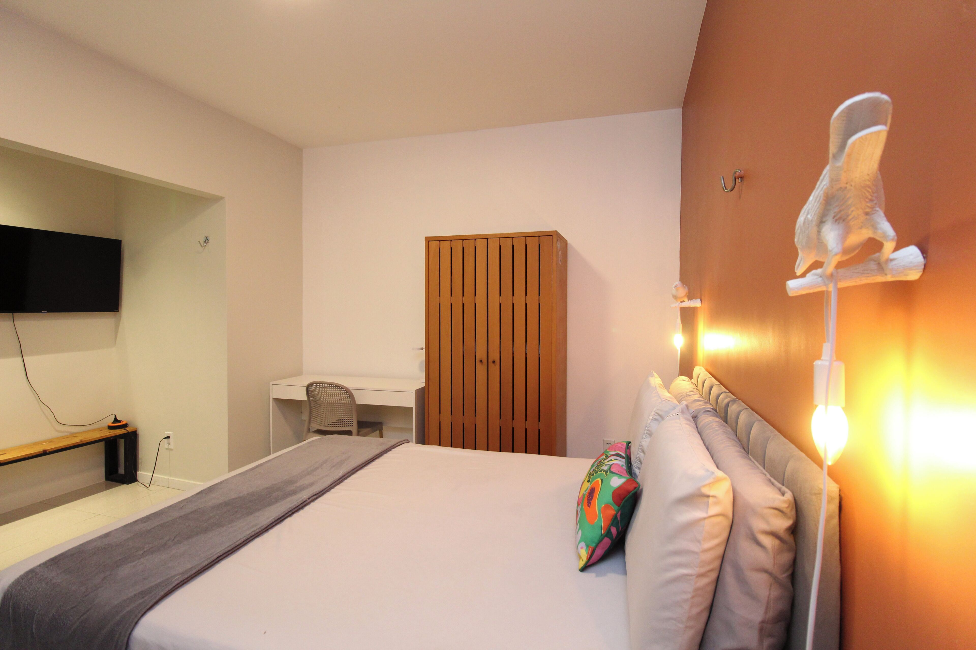 Un dormitorio con cama, mesita de noche, lámpara y un armario de madera.