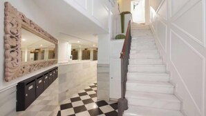 Uma escadaria com paredes brancas e chão quadriculado em preto e branco.