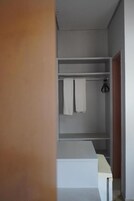 Un baño moderno con un lavamanos blanco, un perchero con dos toallas y una puerta de madera.