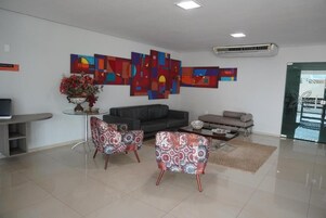 Una sala de estar moderna con un sofá gris, dos sillones estampados, una mesa de centro y arte abstracto en la pared.