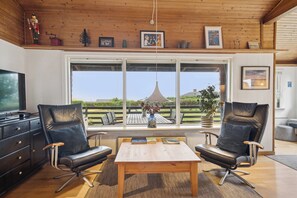 Una sala de estar moderna con dos sillones de cuero, una mesa de centro de madera y un ventanal con vistas al exterior.