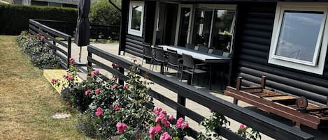 Une cabane en rondins dotée d’un coin repas et d’une terrasse.