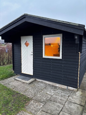 Un piccolo chalet di legno scuro con una porta bianca e una finestra.