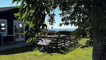 A grassy outdoor area with a wooden deck and a building in the background.