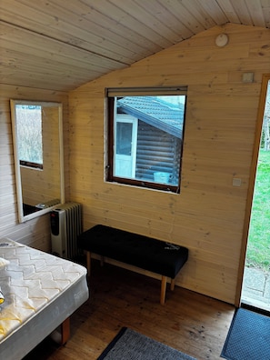 A wooden cabin interior with a bed, bench, window, and radiator. - Holiday home in Horne with sea view (Faaborg)