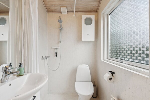 A bathroom with a white sink, toilet, and shower.
