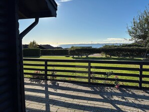 A wooden deck with a view of a grassy area and a distant body of water. - Holiday home in Horne with sea view (Faaborg)