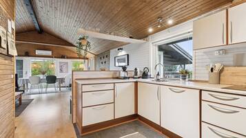A modern kitchen with wooden cabinets, a built-in oven, and a large window.