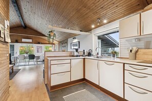A modern kitchen with wooden cabinets, a built-in oven, and a large window. - Holiday home in Horne with sea view (Faaborg)
