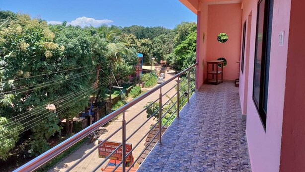 A balcony with a metal railing overlooking a lush green landscape and a clear blue sky. - Saimata Residency (Gokarna)