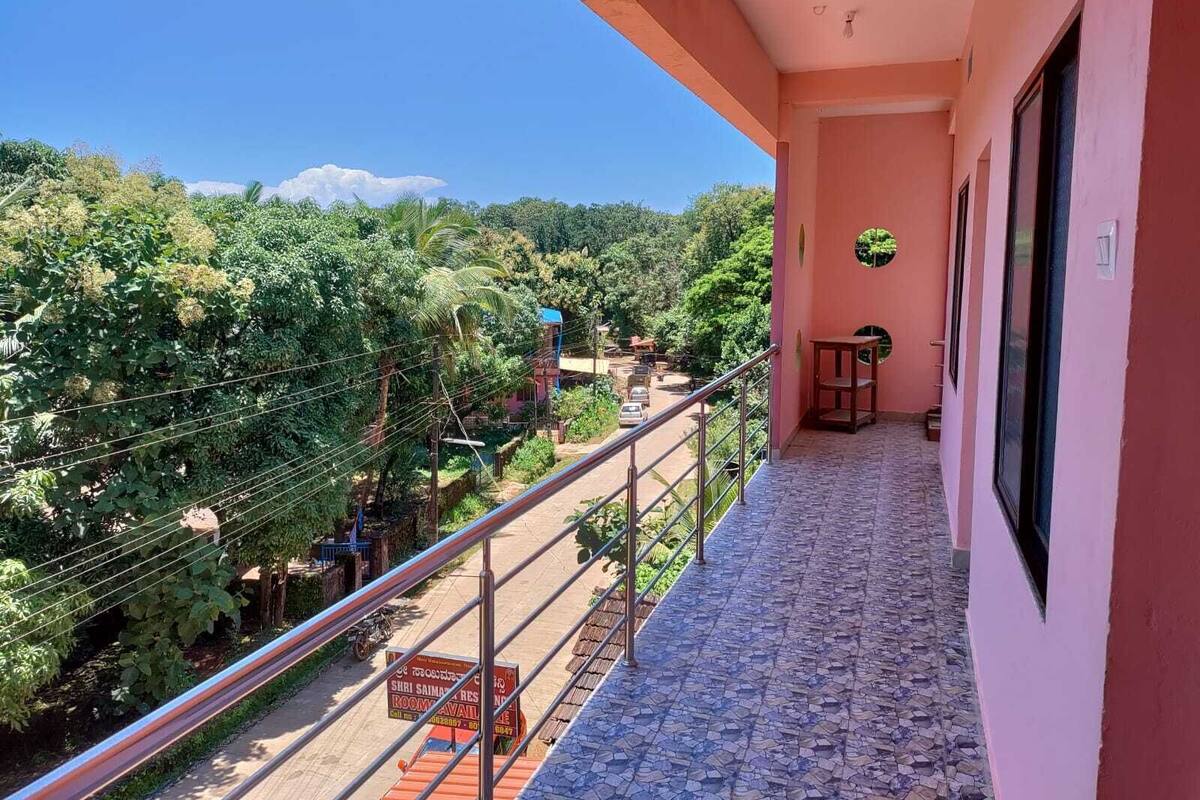 A balcony with a metal railing overlooking a lush green landscape and a clear blue sky.