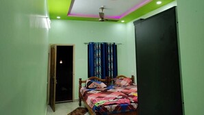 A bedroom with a bed, a ceiling fan, and a door. - Saimata Residency (Gokarna)