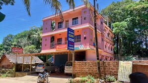 A pink multi-story building with a sign advertising rooms for sale. - Saimata Residency (Gokarna)