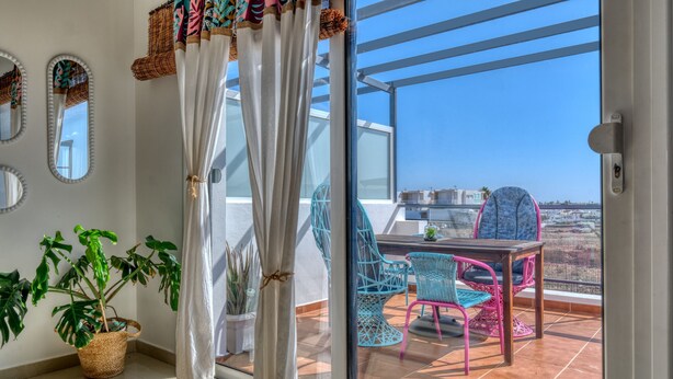 A balcony with a table and chairs, a potted plant, and a view of the city. - THE MERMAID HOUSE-PLAYA HONDA (Playa Honda)