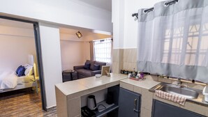 Ein gemütlicher Raum mit Küchenzeile, einem Bett, einer Couch und einem Fenster mit Vorhängen.