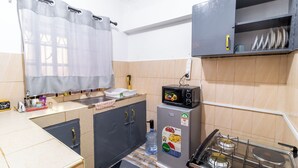 Eine kleine Küche mit Mikrowelle, Kühlschrank und Gasherd.