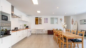 Een moderne keuken met witte kastjes, een houten eettafel en een surfboard aan de wand.