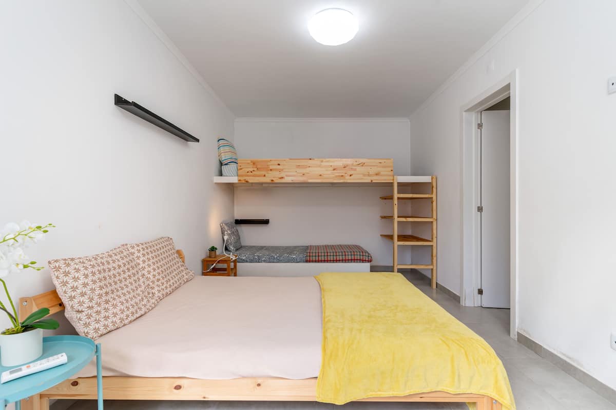 A bedroom with a bunk bed, a bedside table with a plant, and a bedside lamp.