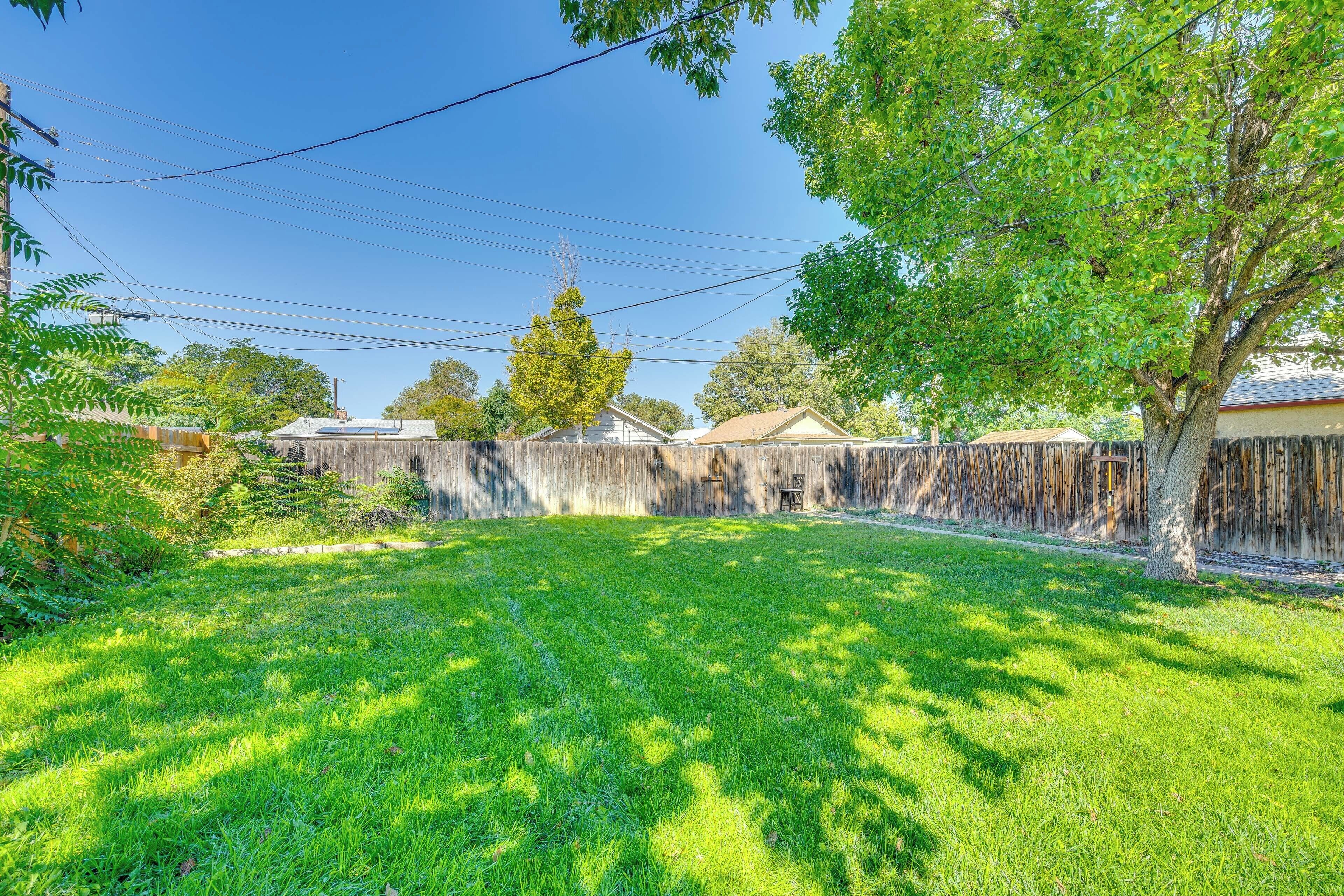 A backyard with a wooden fence, a tree, and a clear sky.