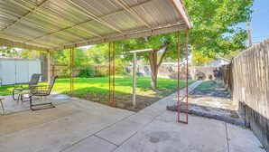 Une terrasse couverte avec un sol en béton, un toit en métal et une clôture en bois en arrière-plan.