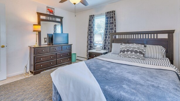 Une chambre à coucher avec un lit, une commode, un téléviseur et un ventilateur de plafond.