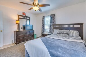 Une chambre à coucher avec un lit, une commode, un téléviseur et un ventilateur de plafond.