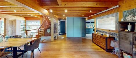 A spacious wooden interior with a dining area, kitchen, and staircase.