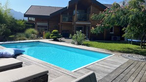 A modern two-story house with a wooden exterior, a swimming pool, and a deck with lounge chairs. - Family House Doussard (Lake Annecy) with swimming pool (Doussard)