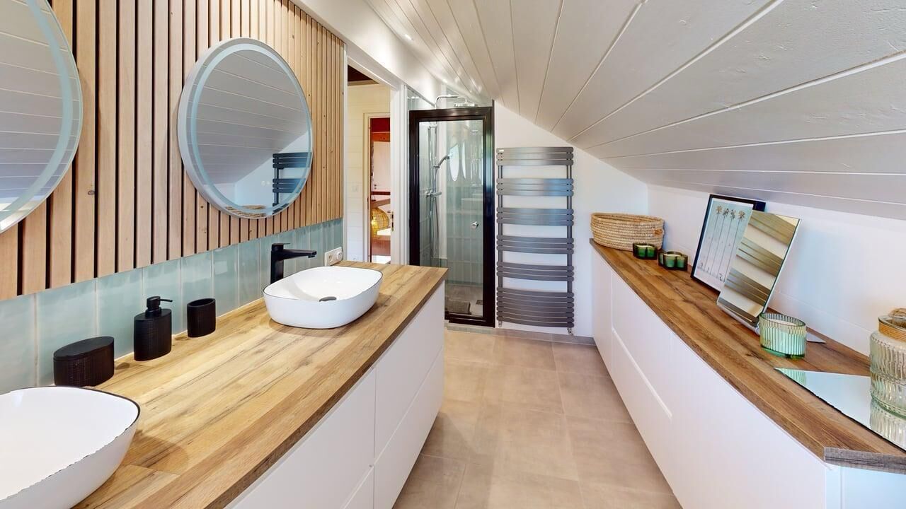 A modern bathroom with a wooden vanity, a large mirror, and a glass shower enclosure.
